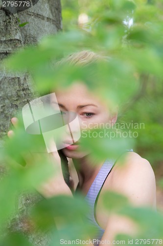 Image of Young woman hugging a tree.