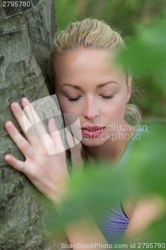 Image of Young woman hugging a tree.