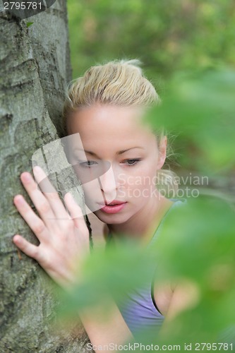 Image of Young woman hugging a tree.