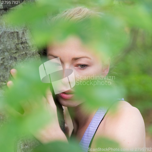 Image of Young woman hugging a tree.