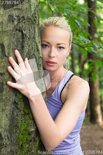 Image of Young woman hugging a tree.