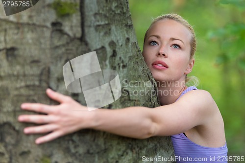 Image of Young woman hugging a tree.