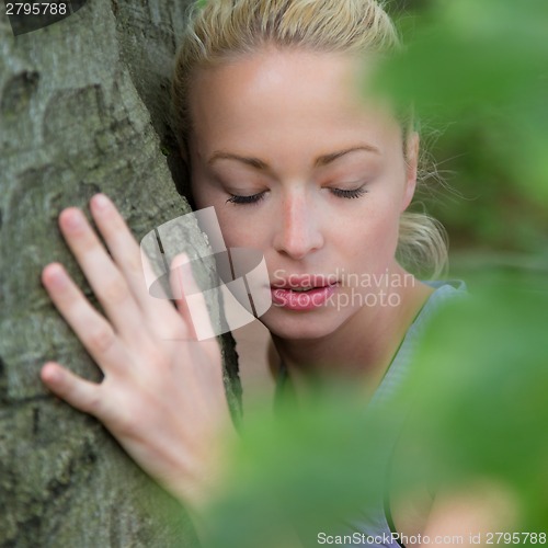 Image of Young woman hugging a tree.