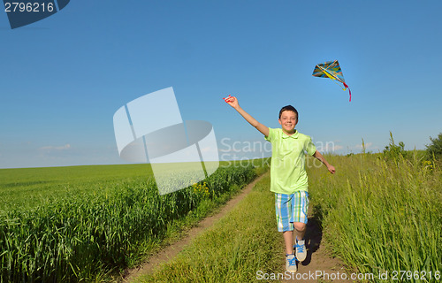 Image of boy playing with kite on greenfield