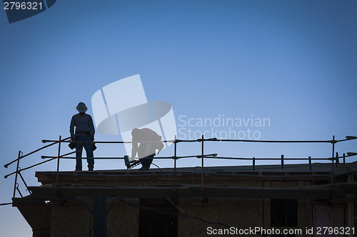 Image of Construction Workers Silhouette on Roof