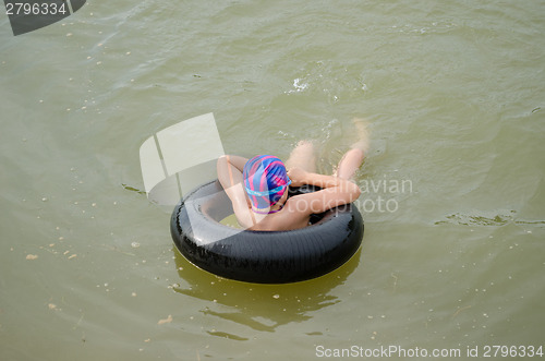 Image of girl with diving hat floating on  tire in water  