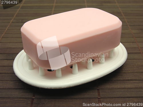 Image of Pink soap on a soap dish on a brown background