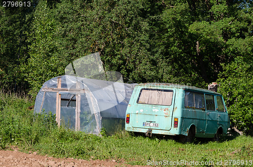 Image of greenhouse and old mini bus in garden meadow  