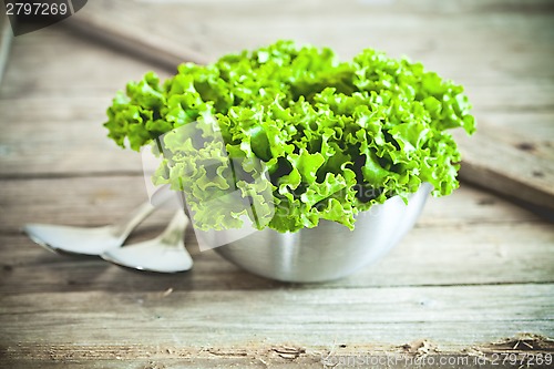 Image of lettuce salad in metal bowl and spoons