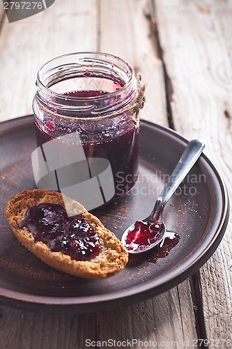 Image of black currant jam in glass jar and crackers