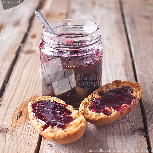 Image of black currant jam in glass jar and crackers 