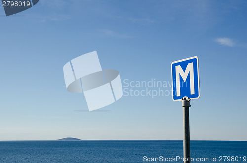 Image of Passing place road sign by the coast with an island in the horiz