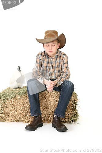 Image of Country boy sitting on lucerne bale
