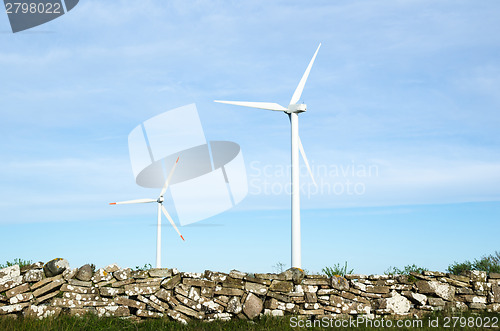 Image of Two wind turbines by an old traditional stonewall at the swedish