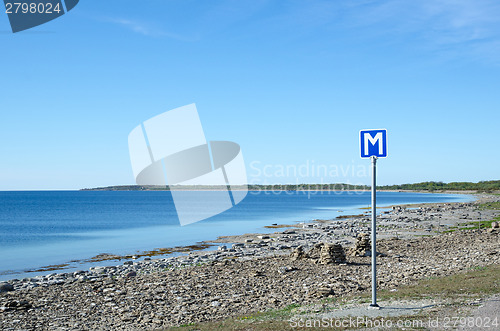 Image of Scandinavian passing place road sign by a road along a flat rock