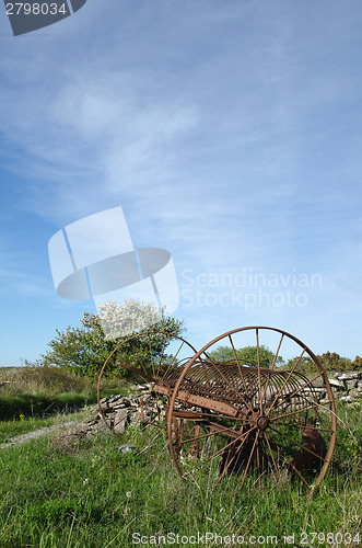Image of Abandoned old horse rake in a landscape at springtime