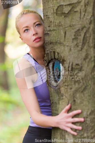 Image of Young woman hugging a tree.