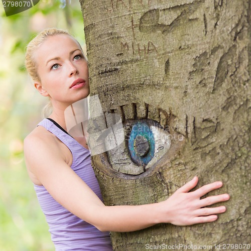 Image of Young woman hugging a tree.