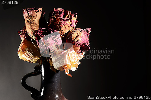 Image of bouquet of dried roses in ceramic vase