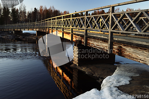 Image of old wooden bridge over the river at sunset
