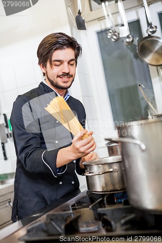 Image of Attractive friendly chef preparing spaghetti