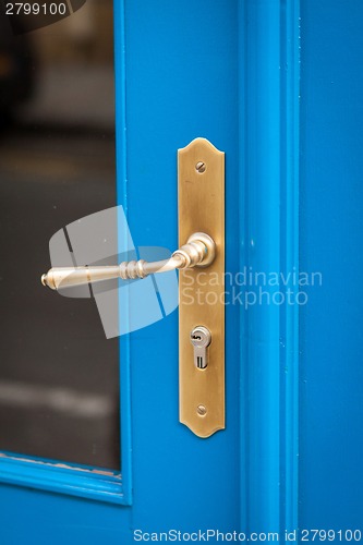 Image of Brass door handle on a colorful blue door