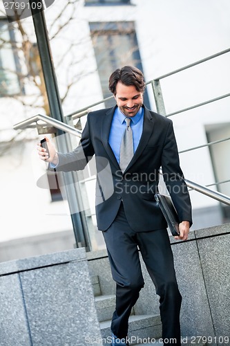 Image of Smiling businessman walking down stairs