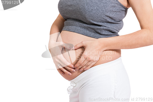 Image of Young pregnant woman making a heart gesture