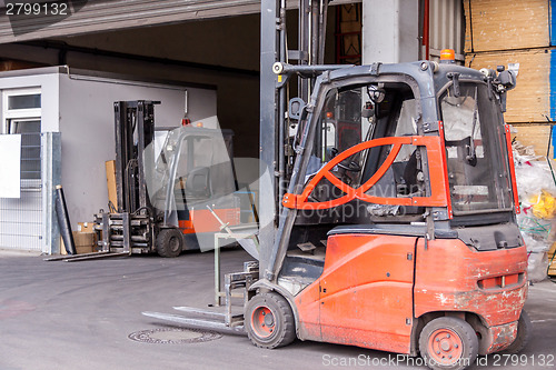 Image of Small orange forklift parked at a warehouse