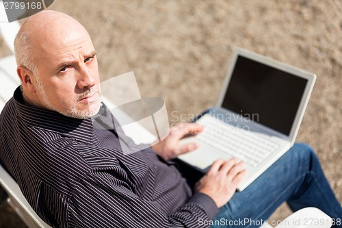 Image of Man sitting on a bench using a laptop