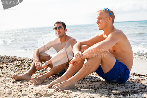 Image of Two handsome young men chatting on a beach