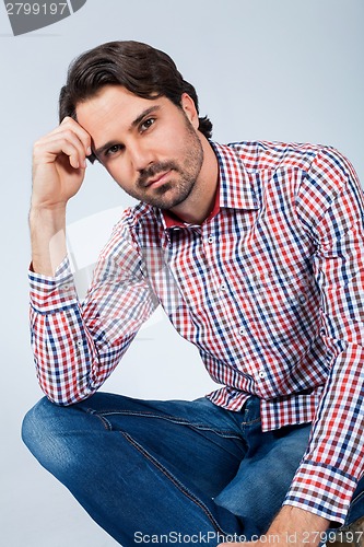 Image of Handsome young man sitting on a wooden box