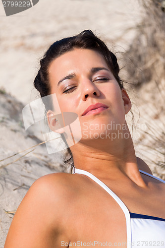 Image of Beautiful woman sitting on golden beach sand