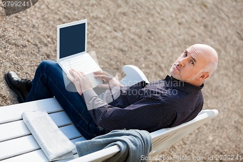 Image of Man sitting on a bench using a laptop