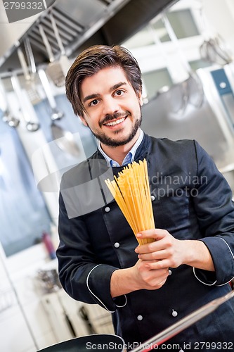 Image of Attractive friendly chef preparing spaghetti