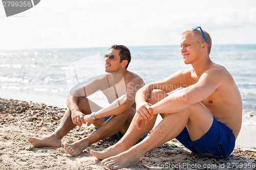 Image of Two handsome young men chatting on a beach