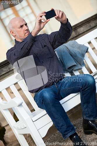 Image of Man taking a photograph with his mobile