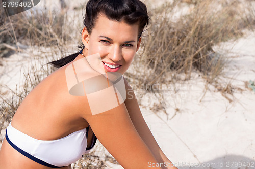 Image of Beautiful woman sitting on golden beach sand