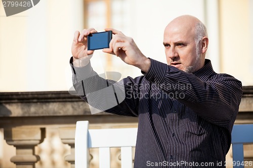 Image of Man taking a photograph with his mobile