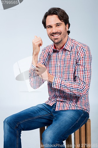 Image of Handsome young man sitting on a wooden box