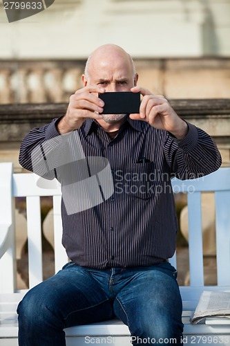 Image of Man taking a photograph with his mobile