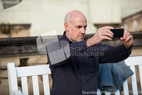 Image of Man taking a photograph with his mobile