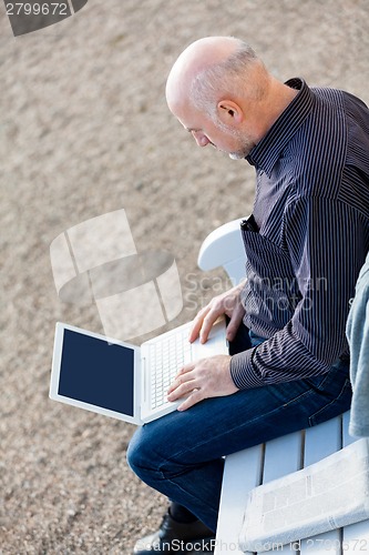 Image of Man sitting on a bench using a laptop