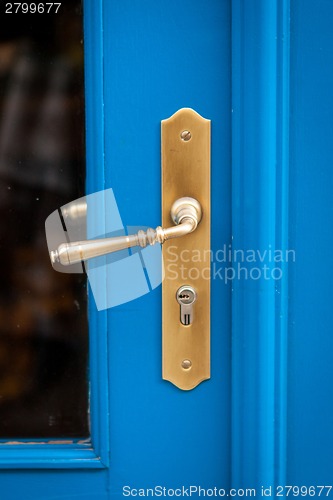 Image of Brass door handle on a colorful blue door