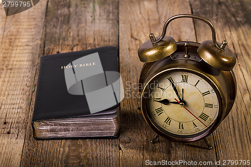 Image of Bible with clock on wood