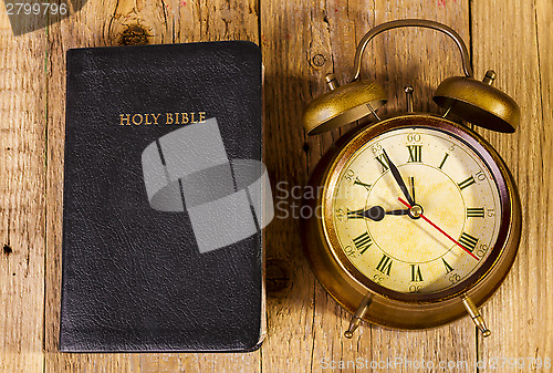 Image of Bible with clock on wood