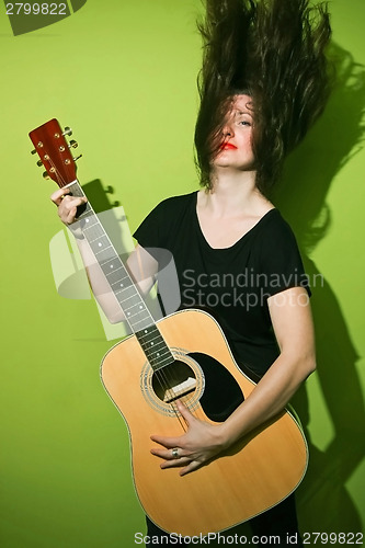 Image of Woman with rock guitar shaking hair 
