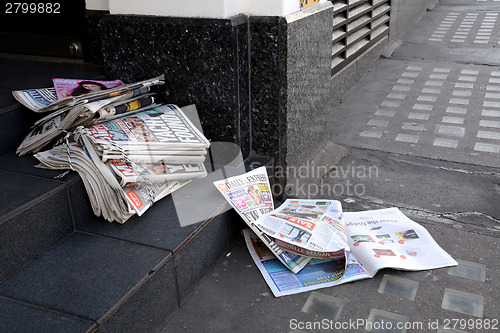 Image of Tabloid newspapers abandoned in a shop doorway