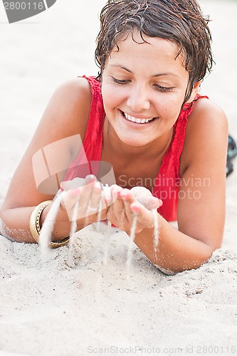 Image of brunet woman in red lying on a sand