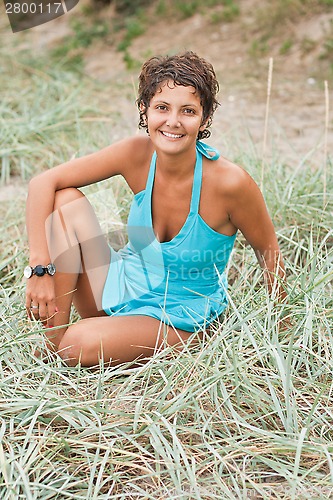 Image of brunet woman in blue sitting in a grass